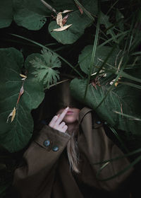 A woman lies in the tall grass and shows the middle finger