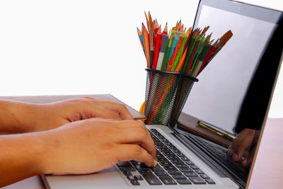 Close-up of person using laptop on table over white background