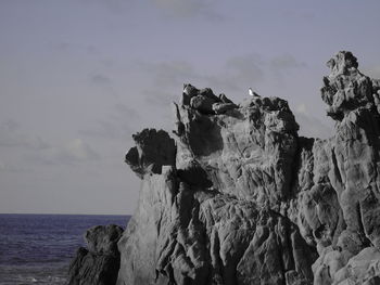 Close-up of rock formation by sea against sky