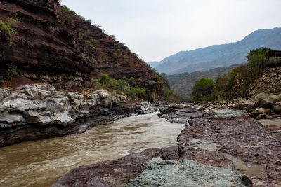 Scenic view of stream amidst rocks against sky