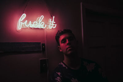 Man looking at illuminated sign on wall