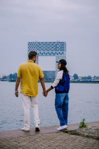 Rear view of people standing on sea shore against sky