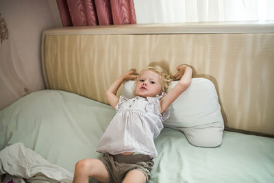 Portrait of young woman sitting on bed at home