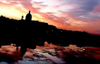 Silhouette of building against cloudy sky at sunset