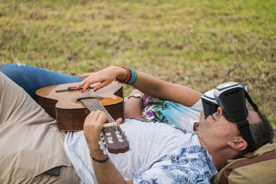 Man and woman wearing virtual reality simulator while playing guitar