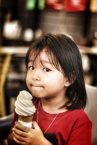 Portrait of cute girl holding ice cream in restaurant