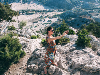 Woman standing on rock by mountain against sky