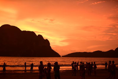 Silhouette people at beach against sky during sunset