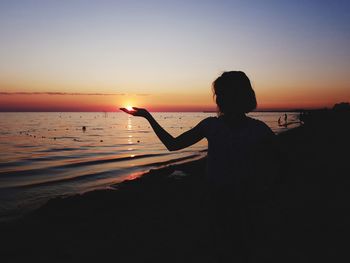 Silhouette person on beach against sky during sunset