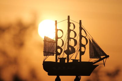 Close-up of toy ship against sky during sunset