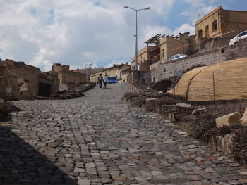 Cobblestone street amidst buildings against sky