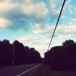 Road by trees against sky