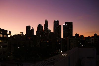 Modern buildings in city against sky during sunset