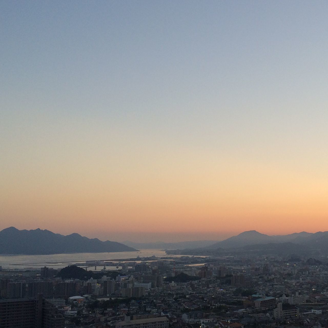 cityscape, city, building exterior, architecture, built structure, sunset, crowded, copy space, clear sky, high angle view, residential district, orange color, residential building, mountain, residential structure, city life, aerial view, outdoors, no people, sky