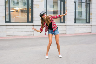 Full length of young woman with arms raised in city