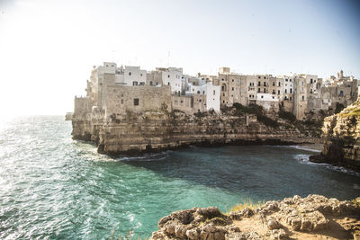 Buildings by sea against clear sky