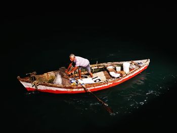 Man sitting on boat moored in sea