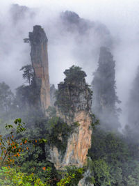 Scenic view of rocky mountains in foggy weather