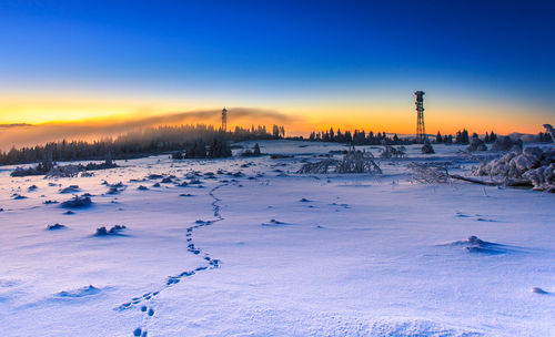 Scenic view of frozen landscape against blue sky during sunset