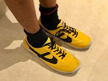Low section of man standing on yellow shoes