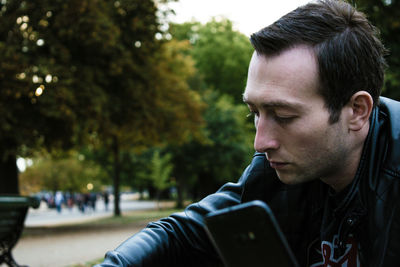 Side view of young man against trees