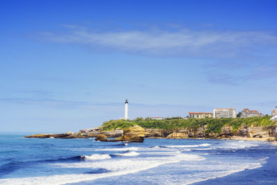 Built structure on beach by buildings against blue sky