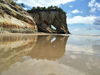 Rock formation on shore against sky