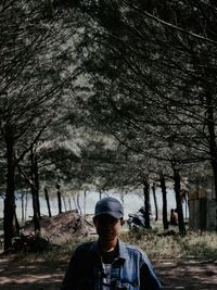 Young man standing against trees