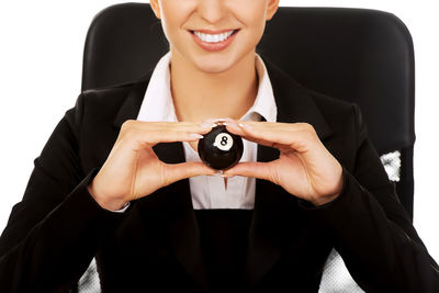 Businesswoman with pool ball at desk against white background