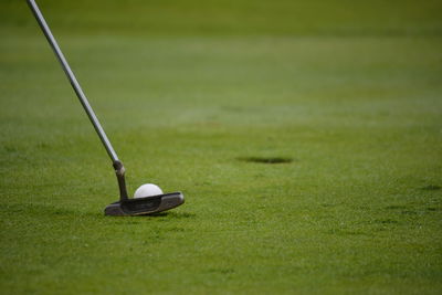 Golf club putting ball in hole