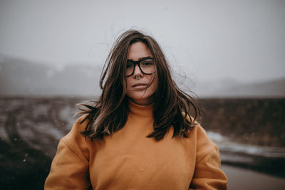 Portrait of beautiful young woman standing against waterfall