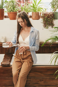 A girl with long hair, in home clothes, drinks clean water from a glass in the bathroom