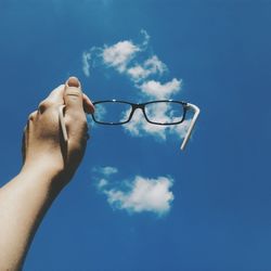 Low angle view of cropped hand against clear blue sky