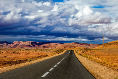 Road leading towards mountains against sky