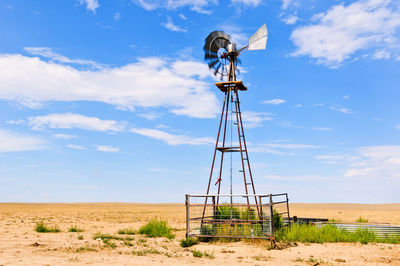 Low angle view of wind turbines on field against sky
