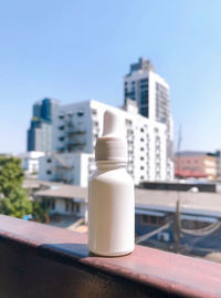 Close-up of bottle against buildings in city