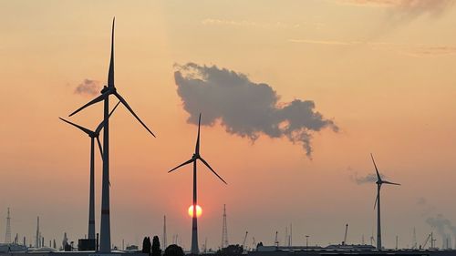 Silhouette of wind turbine against sky during sunset