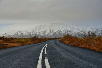 Empty road leading towards snowcapped mountain