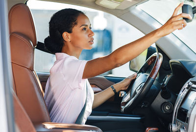 Woman adjusting rear-view mirror in car