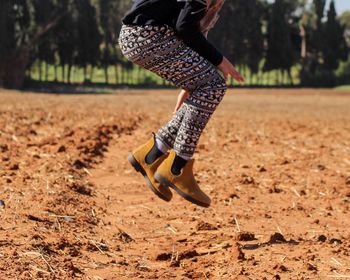 Low section of woman jumping on field