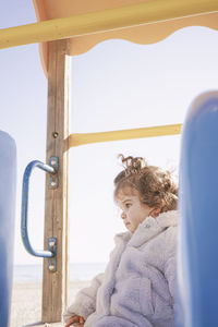 Cute baby girl sitting on slide at playground