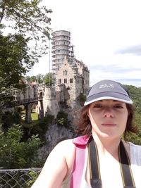 Portrait of young woman standing against built structure