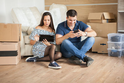 Young woman using phone while sitting on sofa at home