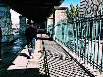 Rear view of man walking on bridge in city