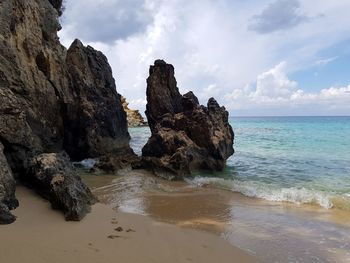 Rock formation on beach against sky