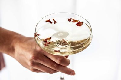 Close-up of hand holding wineglass against white background