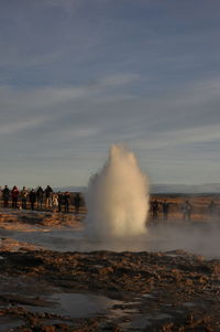 People on shore against sky