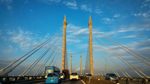 Cars on penang bridge against blue sky during sunny day