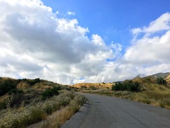 Road by landscape against sky