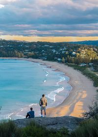 People on beach against sky during sunset